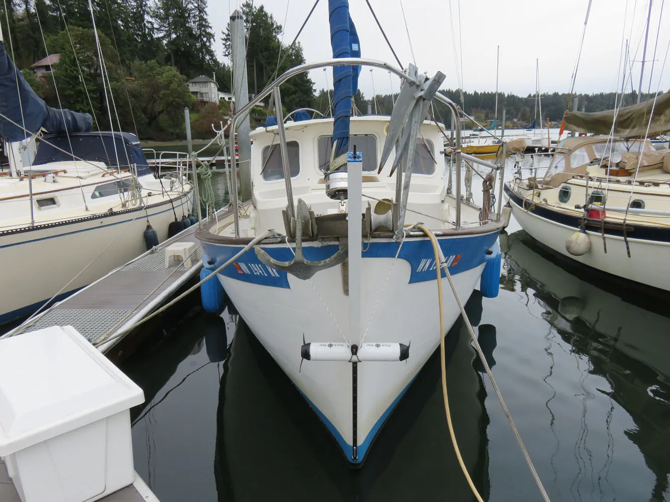 Head-on view of a small trawler in a marina, with a DockStar on a track down the middle of the bow and its white pod raised just above the water, a propeller at each end.