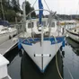 Head-on view of a small trawler in a marina, with a DockStar on a track down the middle of the bow and its white pod raised just above the water, a propeller at each end.