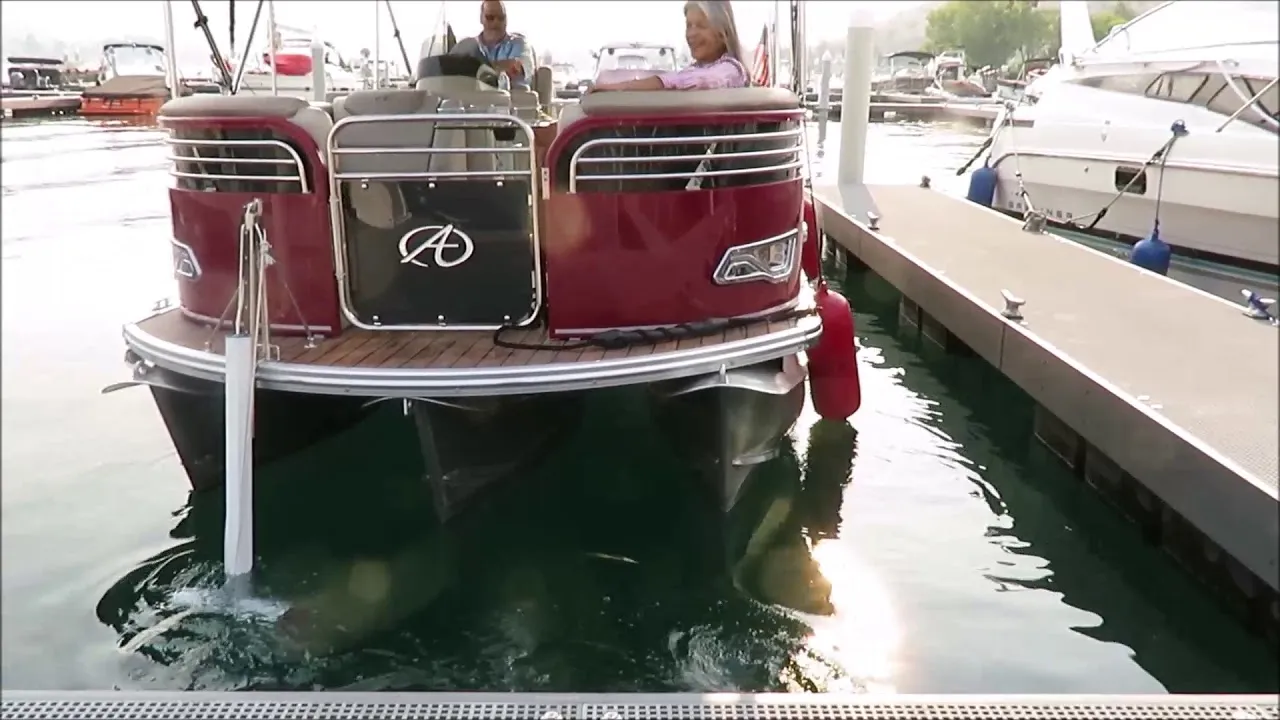 A still from DockStar's pontoon video: a red pontoon boat coming into a dock stern-first, the thruster's white pole down in the water at its corner.