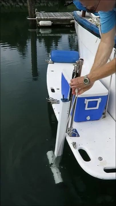 A still from DockStar's stern video, filmed upright on a phone: a hand lowering the thruster on its pole down a track at the edge of a swim platform.